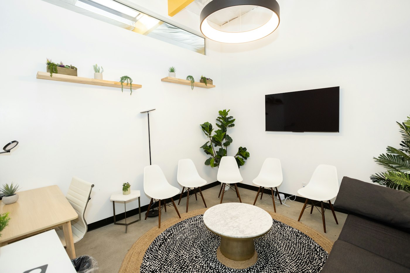 Bright waiting room with white chairs and plants; illustrative stock photograph.